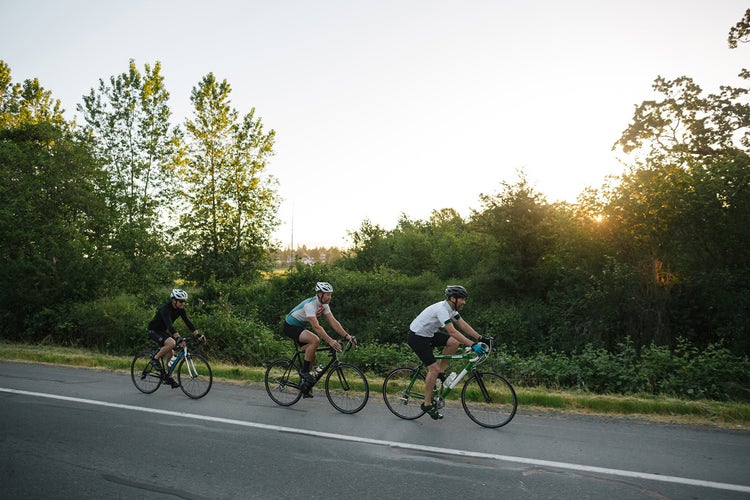 Road cyclists riding hard on a rolling descent — the approach roads between the great cols carry this same sense of controlled momentum