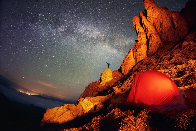 A tent pitched under the Milky Way with mountain scenery — the desert night sky has no equivalent when you